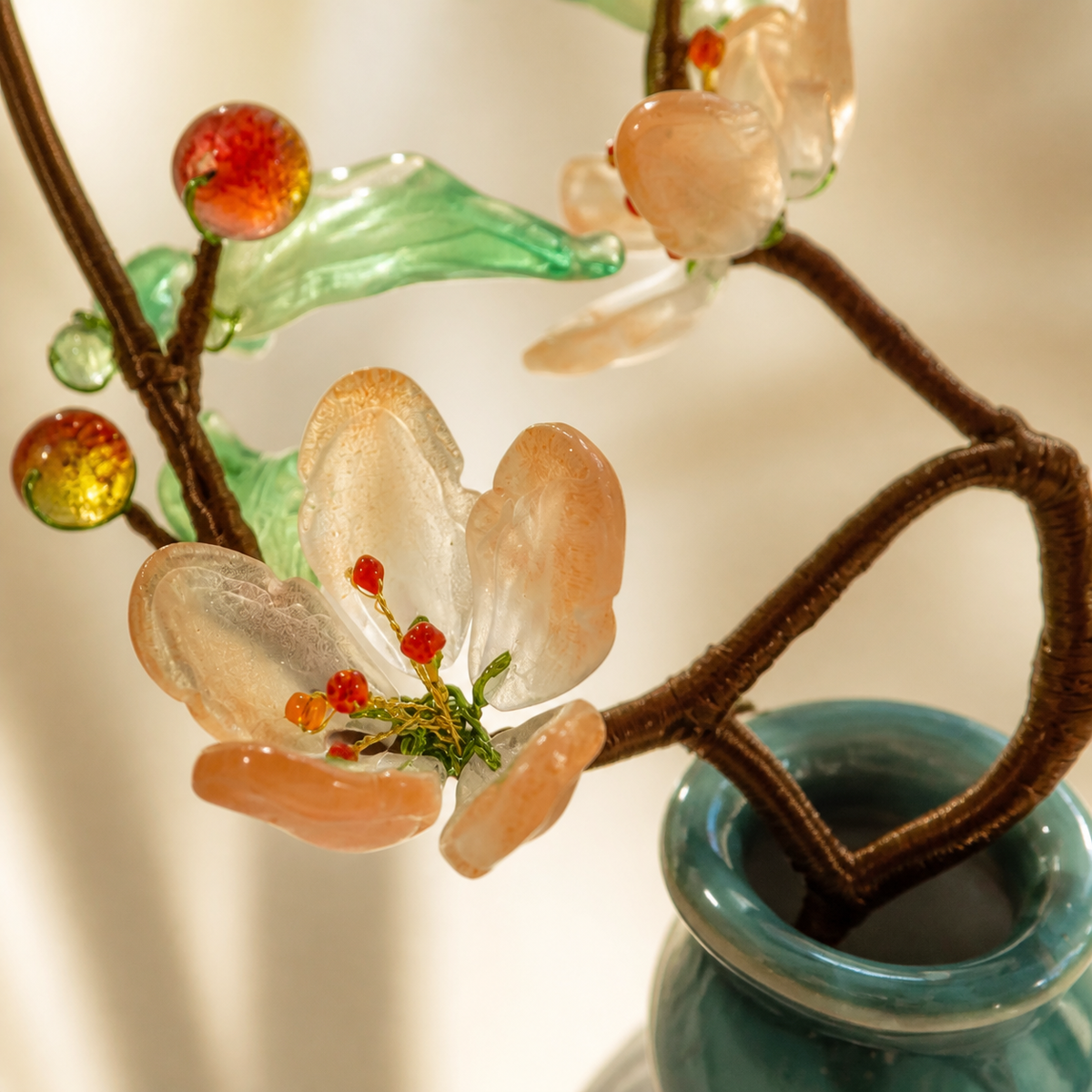 Close-up of blush glass peach blossoms and green leaves