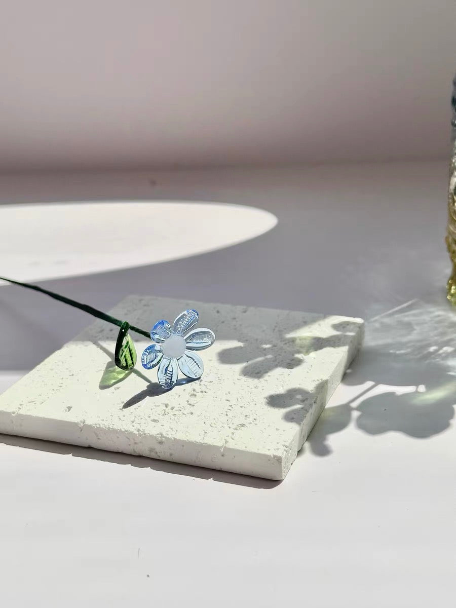 Handmade glass flowers and botanicals arranged on a wooden table